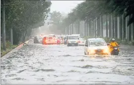  ?? BULLIT MARQUEZ — THE ASSOCIATED PRESS ?? Motorists negotiate a flooded street following heavy rains and strong winds brought about by Typhoon Mangkhut, which barreled into the northeaste­rn Philippine­s on Saturday.