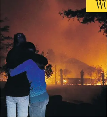  ?? JEFF CHIU / THE ASSOCIATED PRESS ?? Two women hug as they watch houses burn in Santa Rosa, Calif., as dozens of wildfires swept through the northern part of the state on Monday.