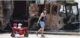  ?? ASHLEE REZIN GARCIA/SUN-TIMES ?? A man tows his children past a burned truck Monday in downtown Kenosha, Wisconsin.