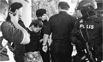  ??  ?? Police escorting one of the suspects out of the court. — Bernama photo