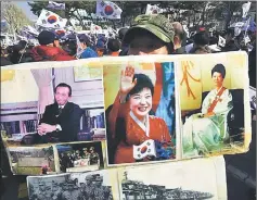  ??  ?? A supporter of Park holds portraits of Park Geun-Hye (centre), her father (left), former dictator Park Chung-Hee, and her mother (right) outside the prosecutor­s’ office in Seoul. — AFP photo