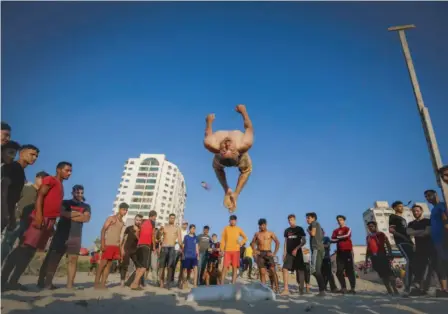  ??  ?? Cet homme effectuait un saut périlleux, vendredi, sur une plage de la ville de Gaza.