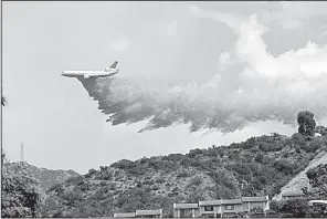  ?? AP/MATT HARTMAN ?? A plane drops fire retardant Saturday on a ridge in Burbank, Calif., as firefighte­rs battle a wildfire.