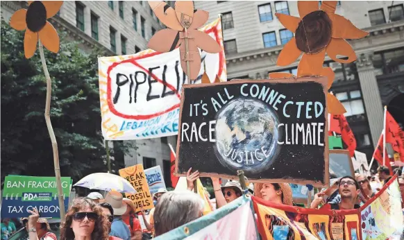  ?? JOHN MINCHILLO, AP ?? Climate change activists carry signs as they march during a protest in Philadelph­ia a day before the start of the 2016 Democratic National Convention.