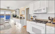  ??  ?? The warm, inviting kitchen looks over the water and out to gardens with flowering trees and successive blooms.