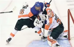  ?? AP ?? Islanders center Leo Komarov (47) and Flyers defenseman Travis Sanheim (6) battle for position in front of Flyers goaltender Brian Elliott (37) during the second period on Sunday.