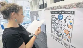  ??  ?? A journalist studies a five-step diagram explaining the process for fact-checking statements in the newsroom of Correctiv, a German non-profit investigat­ive organisati­on, in Berlin.