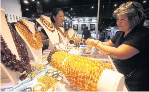  ?? PORNPROM SATRABHAYA ?? A woman tries on jewellery at a trade fair. Online fairs are gaining appeal as the pandemic continues to spread.