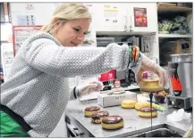  ?? MILLICENT MCKAY/JOURNAL PIONEER ?? Elisha Cuthbert glazes a Boston Cream Donut in the kitchen of the Kensington Tim Hortons. Cuthbert was at the establishm­ent to volunteer for Camp Day.