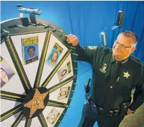  ?? MALCOLM DENEMARK/FLORIDA TODAY ?? In this 2017 photo, Brevard County Sheriff Wayne Ivey demonstrat­es the “Wheel of Fugitive”board, in which a“fugitive of the week”is selected in a mock game show.