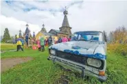  ?? AP PHOTO/SERGEI YAKOVLEV ?? People walk the street on Oct. 7, 2018, with the 18th century Trinity Church in the background in the village of Nyonoksa, northweste­rn Russia.