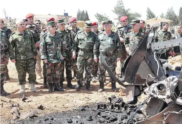  ??  ?? A photo released by the official Syrian Arab News Agency on Friday reportedly shows Syrian Armed Forces chief of staff Ali Abdullah Ayyoub, centre left, visiting Shayrat airfield after American forces fired 59 cruise missiles at the base.