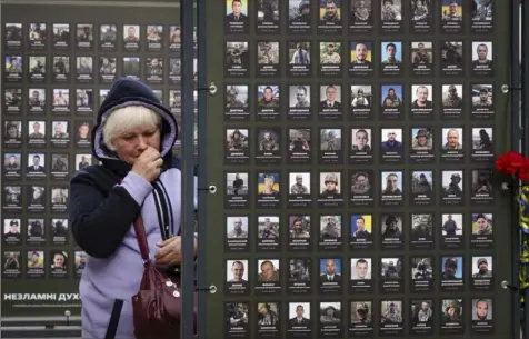  ?? Efrem Lukatsky/Associated Press ?? Liudmila Melnik wipes tears as she looks at a photo of her husband Oleksandr, who was killed in a battle with Russian troops, Wednesday near the City Hall in Kyiv, Ukraine. More than 1,000 photos of Kyiv residents killed in the war have been displayed in front of the City Hall.