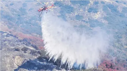  ?? STORY: TCA/PHOTO: REUTERS ?? A helicopter drops water on a hillside fire in Laguna Niguel, California, this week. Scorching heat has also affected Texas and would hit the Midwest and the northeaste­rn US and part of southeaste­rn Canada, AccuWeathe­r said.