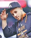  ?? ASSOCIATED PRESS PHOTOS ?? Miami Marlins pitcher Jose Fernandez replaces his cap after the singing of the national anthem before the start of a game in Miami last year.
Top: Miami Marlins players Christian Yelich, right, and Justin Bour react Sunday in front of a memorial on...