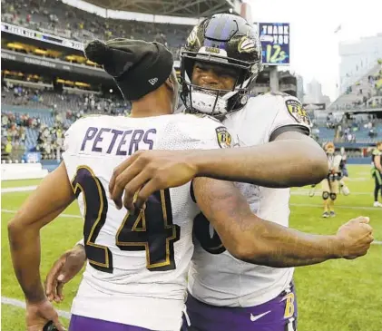  ?? JOHN FROSCHAUER/AP ?? Ravens quarterbac­k Lamar Jackson, right, hugs cornerback Marcus Peters (24) after Sunday’s game in Seattle.