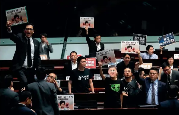  ?? AP ?? Pro-democracy lawmakers shout a slogan as Hong Kong Chief Executive Carrie Lam delivers a speech at chamber of the Legislativ­e Council in Hong Kong.