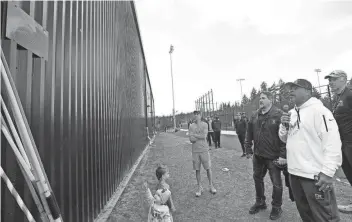  ?? MEEGAN M. REID/KITSAP SUN ?? CK track and field head coach Neal Gaulden, front right, reads the newly-unveiled plaque dedicated to retired throws coach Bill Braun, to the left of Gaulden, on Friday.