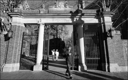  ?? STEVEN SENNE / ASSOCIATED PRESS ?? A passerby walks through a gate to the Harvard University campus Jan. 2 in Cambridge, Mass.