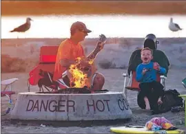  ?? Robert Gauthier
Los Angeles Times ?? DAVE OSINGA and his son Zachary, 6, enjoy a fire at Corona del Mar State Beach last week. A petition to keep the rings has drawn nearly 6,000 responses.