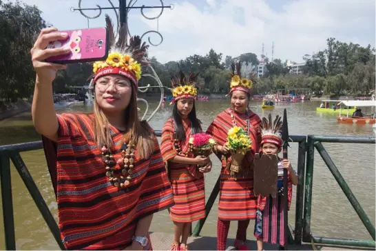  ?? Photo by Jean Nicole Cortes ?? PICTURESQU­E. Tourists enjoy picture taking at the scenic Burnham Lake on a rare sunny day in Baguio City.