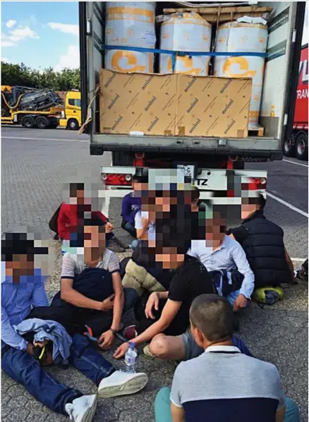  ??  ?? Handcuffed: The migrants, who said they were from Vietnam, sit in front of the lorry they were found in