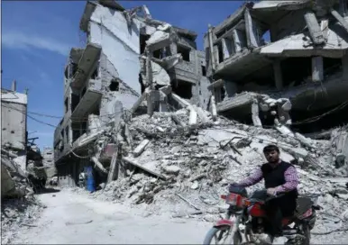  ?? THE ASSOCIATED PRESS ?? A man rides past destructio­n in the town of Douma, the site of a suspected chemical weapons attack, near Damascus, Syria, Monday. Faisal Mekdad, Syria’s deputy foreign minister, said on Monday that his country is “fully ready” to cooperate with the...