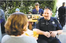  ??  ?? Berkeley police Officer Brandon Smith and Laura Novak chat during the department’s community-engagement event at Caffe Strada.