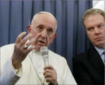  ?? GREGORIO BORGIA — THE ASSOCIATED PRESS ?? Pope Francis, flanked by Vatican spokespers­on Greg Burke, listens to a journalist’s question during a press conference aboard of the flight to Rome at the end of his two-day visit to Ireland, Sunday.
