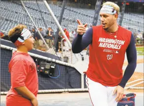  ?? Alex Brandon / Associated Press ?? Meyer Cabrera, 12, left, talks with is dad Washington Nationals second baseman Asdrubal Cabrera during batting practice before Game 3 of the World Series.