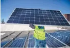  ?? ROBERTO E. ROSALES/JOURNAL ?? Dylan Westerlin of NM Solar Group carries solar panels on the roof of First Presbyteri­an Church in Albuquerqu­e.