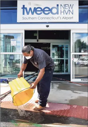  ?? Arnold Gold / Hearst Connecticu­t Media ?? Efrain Nieves of Rescon Restoratio­n & Constructi­on dumps mopped-up water outside a flooded Tweed New Haven Regional Airport terminal in New Haven on Thursday in the aftermath of Ida.
