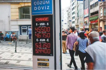  ?? Bloomberg ?? A sign displaying the latest rates for the Turkish lira outside a currency exchange in Istanbul. Fitch is the latest among global credit rating agencies to downgrade Turkey’s ratings.