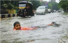  ?? AP ?? A boy plays on a waterlogge­d street. Heavy monsoon rains hit India’s financial hub, flooding several areas and disrupting normal life.