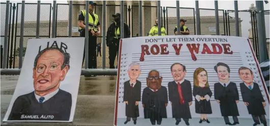  ?? NATHAN HOWARD/GETTY ?? U.S. Capitol Police watch an abortion-rights rally from behind a security fence at the Supreme Court on June 23.