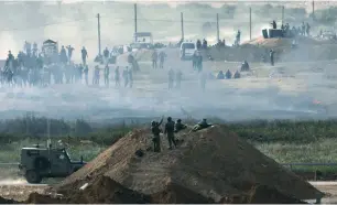  ?? (Amir Cohen/Reuters) ?? SOLDIERS ON Israel’s side of the Gaza border monitor Palestinia­ns gathering on the other side on April 5, the day before the first of several large, weekly Friday protests.