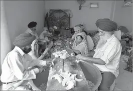  ?? Associated Press ?? Volunteers and devotees cut vegetables as they prepare langar, which translates to community dinner, May 19 at Bangla Sahib Gurudwara, or Sikh temple, in New Delhi, India. Service is one of the most integral traditions of gurudwaras. From cleaning to...