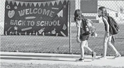  ?? RICK BOWMER/AP ?? Sixth-graders Cimmie Hunter, left, and Cadence Ludlow arrive Aug. 17 at Liberty Elementary School in Murray, Utah, for the first day of the school year.