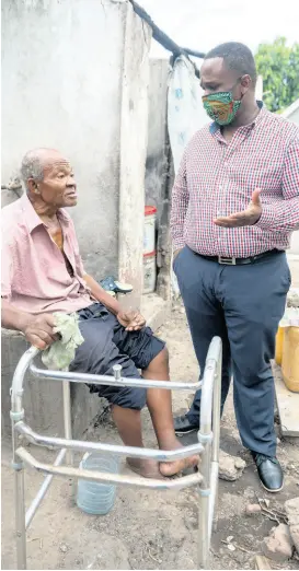  ?? GLADSTONE TAYLOR/MULTIMEDIA PHOTO EDITOR ?? Junior Whyte in dialogue with 60-year-old Allman Town resident Tyrone Phillips in their Kingston community on Wednesday. Phillips is one of several elderly and disabled persons assisted by Whyte with groceries and other supplies.