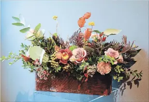 ??  ?? Penney uses a vintage drawer for an arrangemen­t of roses, dried seed heads, foliage and berries.