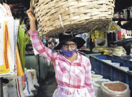  ?? AFP ?? Una vendedora de frutas, con una mascarilla protectora, se abre paso en un mercado popular en Managua, donde la respuesta al covid-19 inquieta a la Organizaci­ón Panamerica­na de la Salud.