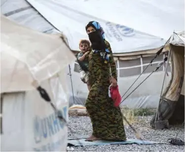  ?? — AFP ?? HASAN SHAM, Iraq: An Iraqi woman carries a child at the Hasan Sham camp for internally displaced people. Tired and traumatize­d, Iraqi mothers who fled Mosul struggle to breastfeed or buy baby formula milk for their babies.