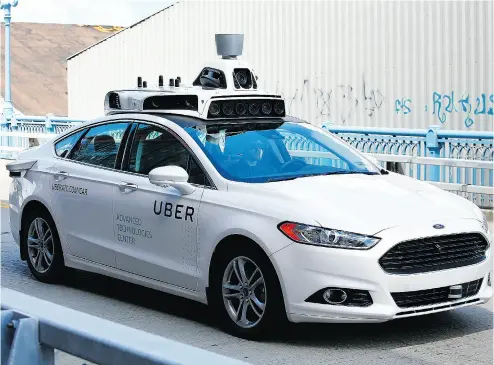  ?? JARED WICKERHAM / THE ASSOCIATED PRESS ?? A self- driving Ford Fusion hybrid car is test driven in August in Pittsburgh. Ford says profit will slump in 2017 as it invests in autonomous and electric vehicles, and as a used- car glut pinches its bottom line.