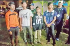  ?? GRK ?? Four men stand next to police on Phnom Penh’s riverside after they were arrested for crimes at Water Festival earlier this week.