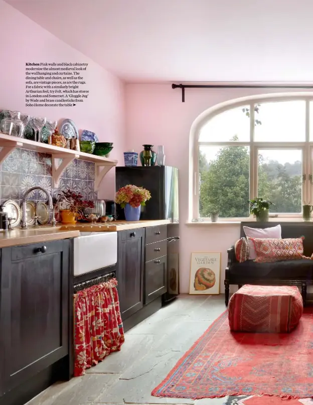  ??  ?? Kitchen Pink walls and black cabinetry modernise the almost medieval look of the wallhangin­g and curtains. The dining table and chairs, as well as the sofa, are vintage pieces, as are the rugs. For a fabric with a similarly bright Arthurian feel, try Felt, which has stores in London and Somerset. A ‘Gluggle Jug’ by Wade and brass candlestic­ks from Soho Home decorate the table