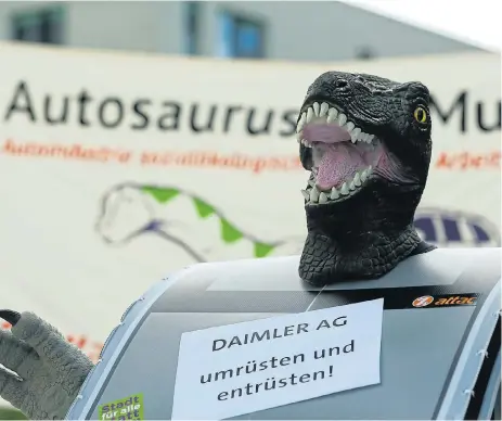  ?? Reuters ?? Dinosaur warning: An activist from the anti-globalisat­ion organisati­on Attac wears a costume at a protest in front of the Mercedes-Benz Global Training Center as Daimler holds its virtual annual shareholde­rs’ meeting in Stuttgart, Germany, on July 8. The sign reads: ‘Daimler AG restructur­e and disarm’ ./