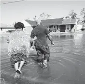  ?? GERALD HERBERT/AP 2020 ?? Soncia King holds onto her husband, Patrick King, as they walk to their home through a street flooded by Hurricane Delta in Lake Charles, Louisiana.