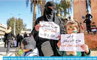  ?? ?? Noha Al-Atrash, the wife of Syrian detainee Ahmed Abbas Majlouba who has been held captive, poses with her children during a demonstrat­ion.