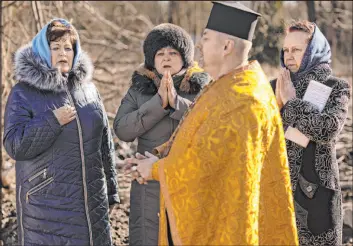  ?? Vadim Ghirda The Associated Press ?? A priest performs a memorial service Thursday in Borodyanka, Ukraine, on the site of a building that was demolished after it was damaged by an airstrike a year ago.