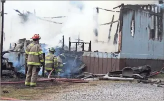  ?? / Spencer Lahr ?? Rome-Floyd County firefighte­rs blast water beneath the floor of a mobile home at 826 McGee Bend Road on Monday evening.